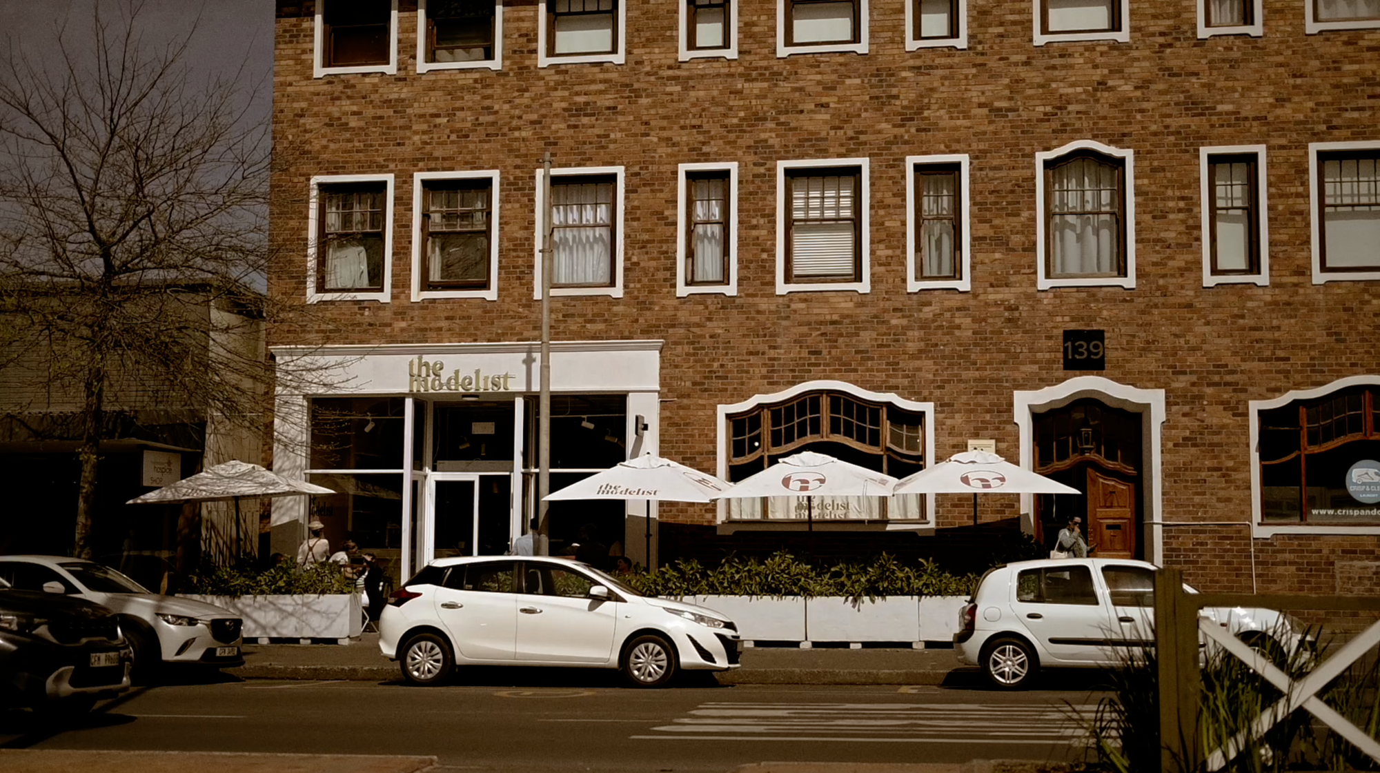 Brick building with outdoor seating area and cars parked in front, Somerset West
